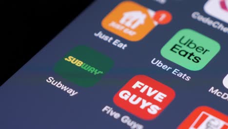 Smartphone-screen-with-various-food-delivery-apps,-user-swiping,-focus-on-Subway-app-icon,-blurred-background