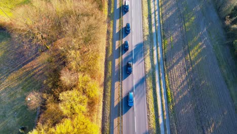 Bird's-Eye-View-of-Vehicles-on-a-Country-Road-Casting-Long-Shadows-at-Dusk