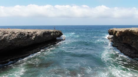 Tourist-watching-waves-crashing-into-rugged-cliffs-at-Shete-Boka-National-Park,-Curacao,-wide-aerial-view