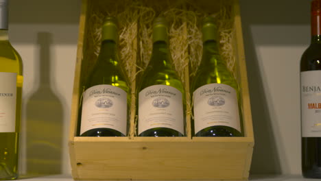 White-wine-bottles-stored-in-open-wooden-box-with-hay,-dolly-in