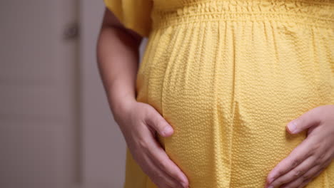 Clutching-and-stroking-her-bulging-baby-bump,-the-expectant-pregnant-woman-is-feeling-the-movement-of-the-baby-in-her-stomach