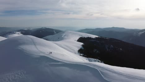 Hikers-in-Iezer-Papusa-Mountains,-Romania-during-winter,-aerial-view