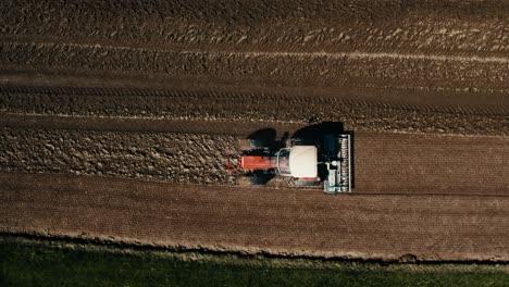 Luftaufnahme-Eines-Einsamen-Traktors,-Der-Bei-Sonnenuntergang-Fruchtbare-Felder-Pflügt