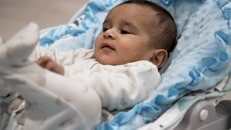 A-six-month-old-infant-lies-leisurely-in-their-baby-basket,-displaying-curiosity-and-relaxation,-embodying-the-concept-of-early-exploration-and-comfort-in-infancy