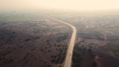 Toma-Aérea-De-Un-Drone-De-Un-Camino-Rural-De-Aldea-A-Través-De-Tierras-De-Cultivo-Durante-La-Tarde-En-Madhya-Pradesh,-India