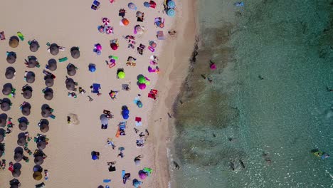 Retreating-drone-shot-of-the-beachfront-of-Cala-Agulla,-a-popular-getaway-for-tourists-located-in-Mallorca,-Spain