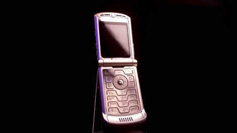 Spinning-Motorola-Razr-V3-Opened-Flip-Mobile-Phone-on-Black-Background