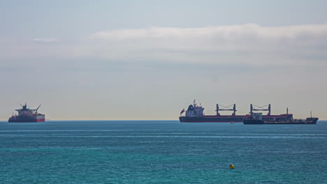 Riesige-Industriefrachtschiffe-Auf-Dem-Meer,-Kleine-Boote-Fahren-Vorbei,-Zeitraffer