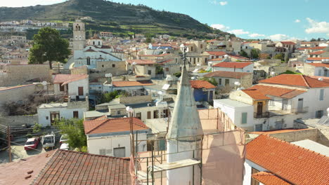 Village-of-Lefkara-in-Cyprus-is-beautifully-captured-in-an-aerial,-revealing-a-maze-of-stone-houses-with-red-tiled-roofs,-interwoven-with-narrow-streets-and-set-against-a-backdrop-of-rolling-hills