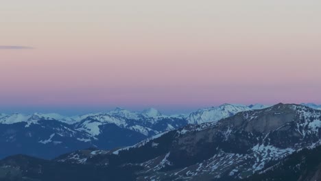 Marvel-at-the-picturesque-silhouette-of-a-snow-covered-mountain-range-during-sunrise,-captured-from-a-drone-perspective