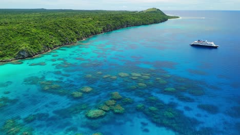Drone-Volando-Hacia-Atrás-Sobre-Arrecifes-De-Coral-En-Fiji-Con-Crucero-Anclado-Frente-A-La-Costa