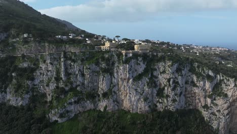 Vista-Del-Acantilado-De-Capri,-Italia,-Con-Edificios-Históricos-Y-Exuberante-Vegetación,-Bajo-Un-Cielo-Despejado