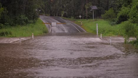 Gold-Coast,-Queensland,-16-February-2024---Medium-shot-of-flooding-across-Hardy's-Road-in-Mudgeeraba-after-heavy-rains-continue-to-lash-South-East-Queensland,-Australia