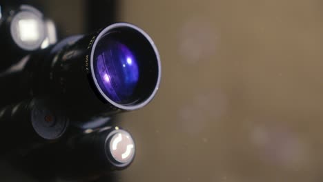 Close-up-of-the-lens-of-a-16mm-film-camera-with-a-purple-hue-reflecting-off-it