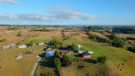 Aerial-view-over-a-farm-and-countryside-fields-of-Chiloe,-sunny-day-in-Chile