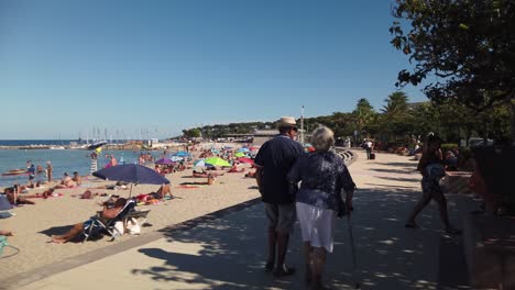 People-walk-by-Plage-du-Ponteil-in-summertime-Antibes,-French-riviera