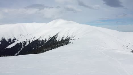 Vast-snowy-landscape-of-Papusa-Peak-in-Iezer-Papusa-Mountains-under-cloudy-skies