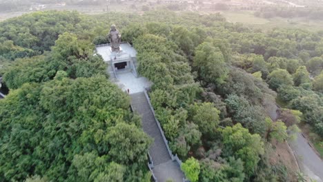 Drone-aerial-view-in-Vietnam-flying-over-buddhist-temple-area-with-pagodas-and-roads-covered-with-green-trees-in-Ninh-Binh-at-sunset