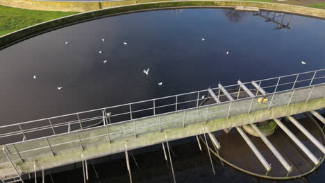 Aerial-view-circling-bridge-crossing-waste-water-circular-sewage-filtration-tank-close-up
