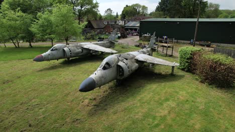 Royal-Navy-Sea-Harrier-FRs1-aerial-view-orbiting-pair-of-display-aircraft-in-aerospace-logistics-yard,-Charlwood,-Surrey