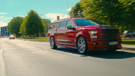 Tracking-Pan-shot-of-a-2018Cherry-Red-Ford-Shelby-Super-snake-driving-down-a-road-in-Estonia