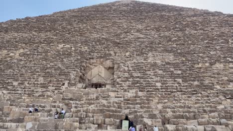 Sunlight-hits-the-apex-of-the-Great-Pyramid-with-an-entrance-visible,-clear-sky