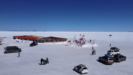 Aerial-pulls-back-from-tourists-at-Plaza-of-Flags-on-Uyuni-Salt-Flat