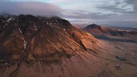 Aerial-landscape-view-of-typical-icelandic-mountain-peaks,-with-a-dramatic-evening-cloudscape