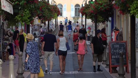 People-walk-by-shops-in-Old-Town-Antibes,-France,-couple-holding-hands