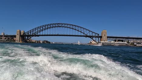 Sydney-harbour-bridge-and-opera-house-in-distance-viewed-from-behind-boat-wake