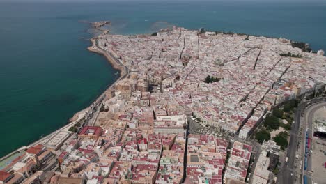 aerial-panning-footage-of-ancient-Cadiz-cathedral-with-view-of-coastal-zone-and-old-town,-Cadiz-Spain