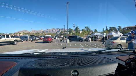 POV---Driving-thru-the-busy-parking-lot-for-a-farmer's-market-located-in-the-parking-lot-for-a-horse-race-track