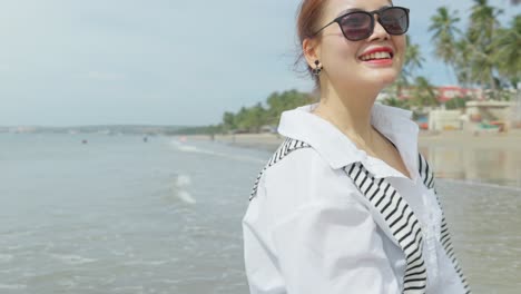 Asian-girl-barefoot-walking-on-sand-at-the-beach-with-beautiful-coconut-trees-in-the-background