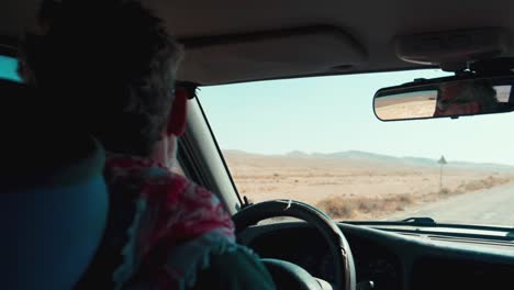 Older-Male-Tour-Guide-Driving-Down-Desert-Road-in-Middle-of-Day,-Slow-Motion
