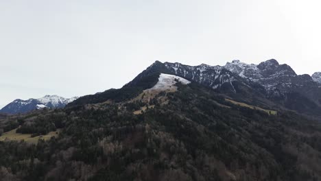 Luftaufnahme-Von-Der-Spätwinterlichen-Berglandschaft,-Grünen-Wäldern-Und-Schneebedeckten-Bergen,-Österreich