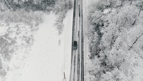 Drone-footage-of-car-driving-in-the-winter-forest-road