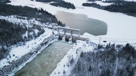 Disparo-Aéreo-De-Drones-Agua-Corriendo-Notigi-Energía-Hidroeléctrica-Presa-Del-Lago-En-El-Invierno-Nevado-Del-Norte-De-Manitoba-Canadá