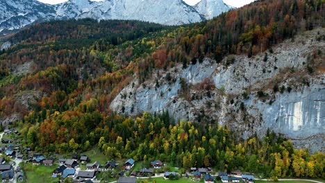 Ein-Lebendiges-Bergdorf-Mit-Farbenfrohen-Häusern-Inmitten-üppiger-Vegetation-Und-Schneebedeckten-Gipfeln,-Aufgenommen-Aus-Der-Luftperspektive-Bei-Klarem,-Sonnigem-Wetter