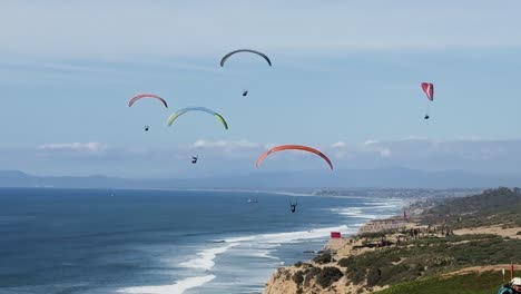 Seven-para-gliders-flying-around-on-a-beautiful-sunny-day-with-ocean-and-cliffs-in-the-background-at-Torrey-Pines-Gliderport-in-La-Jolla,-California