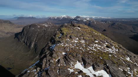 aerial-hiker-on-summit-of-sgurr-an-fhidhleir,-coigach,-highlands,-scotland,-big-landscape-reveal