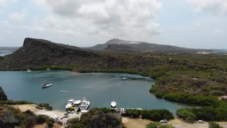 Playa-De-Remolcadores-En-Curazao-Con-Barcos-En-Aguas-Cristalinas-Y-Colinas-Escarpadas,-Vista-Aérea