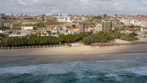 Vista-Aérea-De-La-Playa,-Palmeras-Y-La-Ciudad-Circundante,-Praia-Do-Futuro,-Ceara,-Brasil.