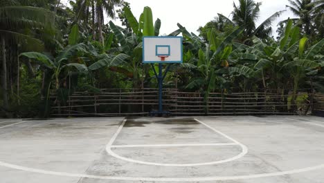 Aerial-Drone-Fly-Low-above-Cemented-basketball-field-in-tropical-jungle-surroundings