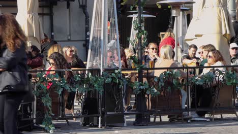 Pedestrians-pass-by-people-sitting-at-outdoor-bar-in-Stockholm,-Sweden