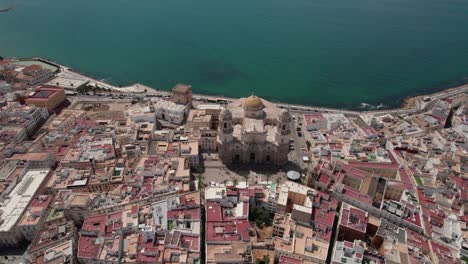 aerial-circle-pan-footage-of-ancient-Cadiz-cathedral-with-view-of-coastal-zone-and-old-town,-Cadiz-Spain