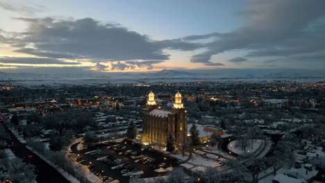Epic-sunset-sky-and-clouds-with-snowcapped-mountain-with-beautiful-historic-Logan-Utah-LDS-temple,-aerial-dolly