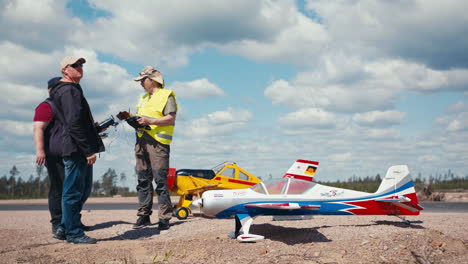 Three-model-aircraft-pilots-with-two-airplanes-getting-ready-for-flying-at-small-airfield-in-Finland