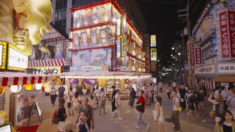 Toma-En-Cámara-Lenta-Y-En-Movimiento-De-Las-Bulliciosas-Calles-Del-Distrito-De-Ebisu-Higashi,-Repletas-De-Vibrantes-Luces-De-La-Ciudad-Y-Una-Enérgica-Vida-Nocturna-En-Osaka,-Japón