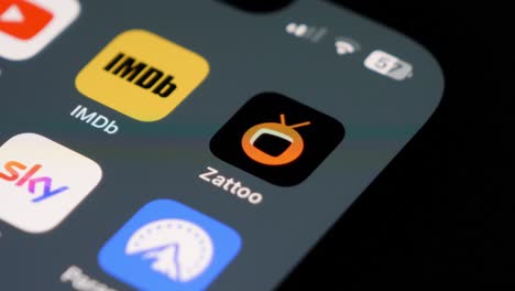 Close-up-of-user-swiping-on-a-smartphone,-Zattoo-app-icon-in-focus