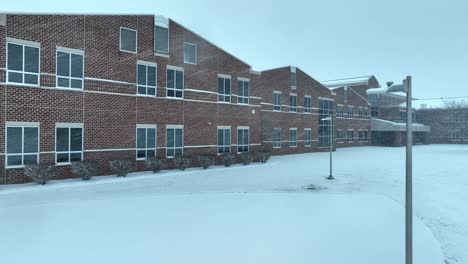 Edificio-Escolar-De-Ladrillo-Americano-Cubierto-De-Nieve-Con-Grandes-Ventanales